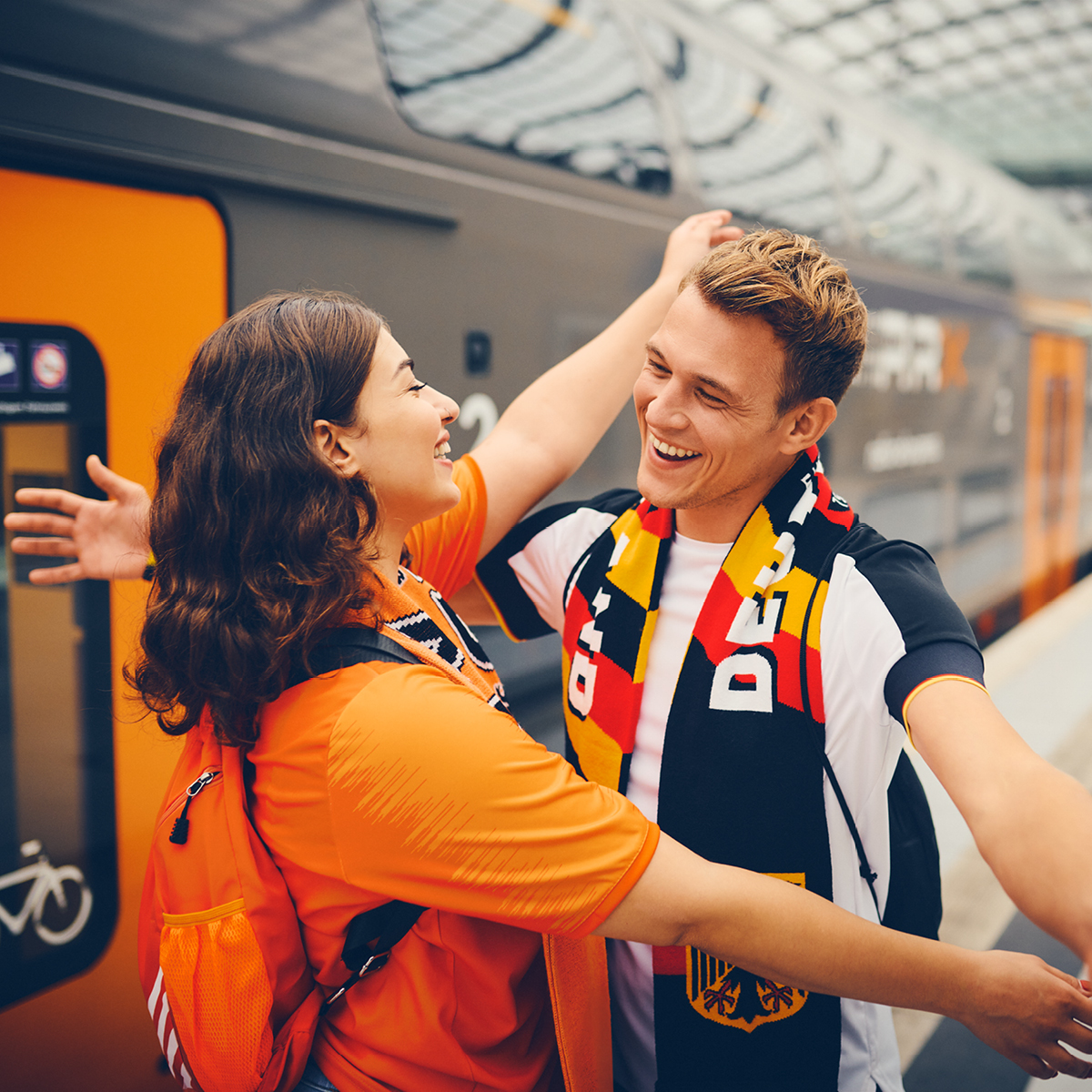 Zwei Fußball-Fans umarmen sich am Bahnsteig.